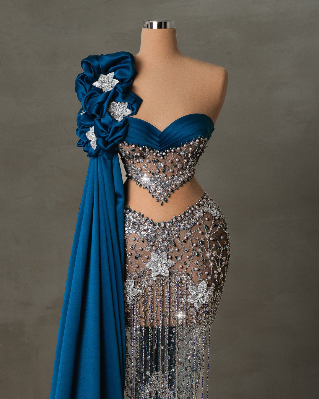 Alyah blue dress with crystal embellishments and floral details, featuring a one-shoulder drape and intricate beadwork.