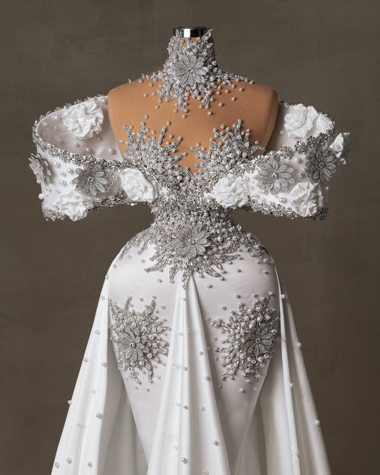 Elegant off-shoulder bridal dress with pearls, crystals, and satin flowers
