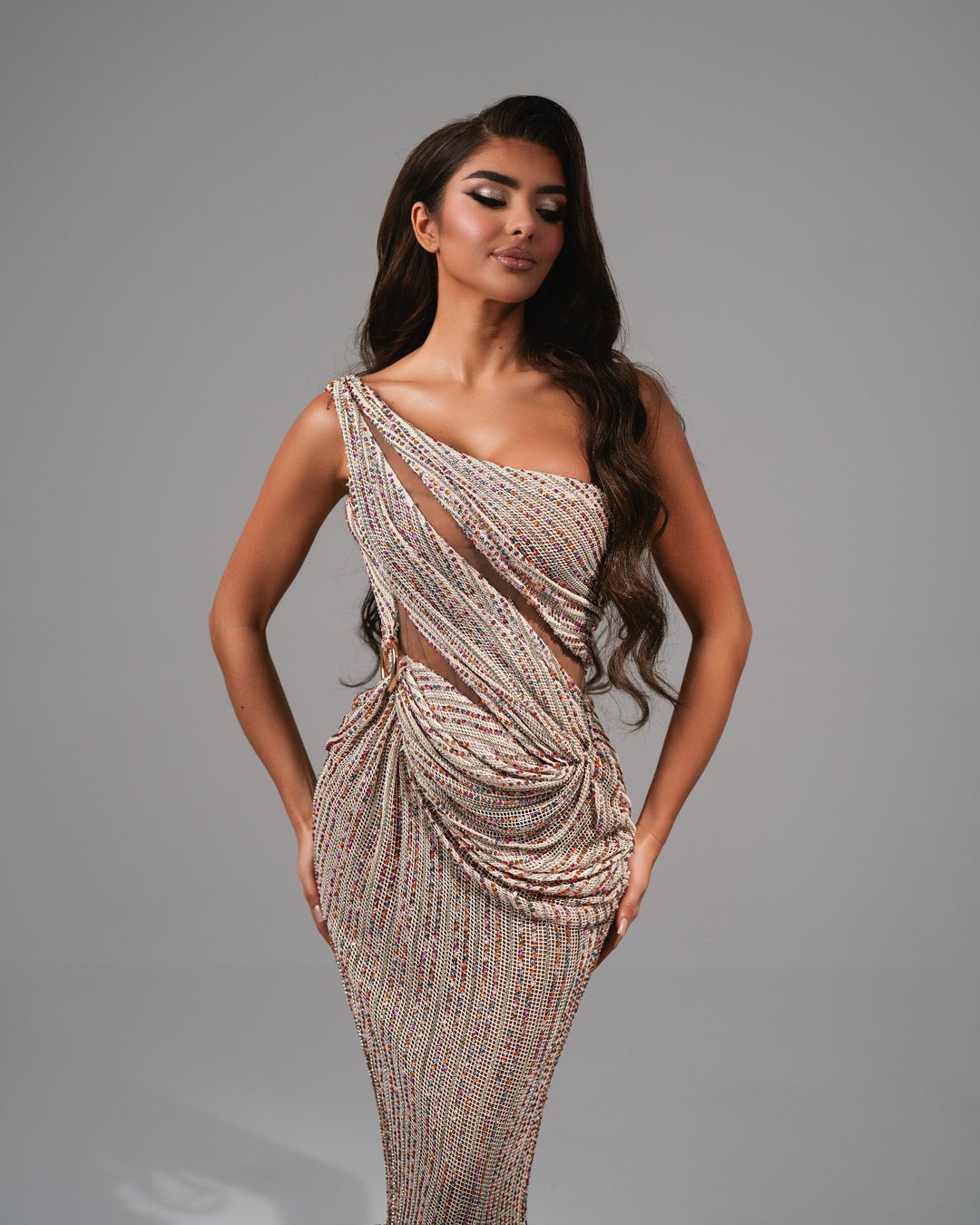 Elegant one-shoulder gown adorned with multicolored stones and side draping.