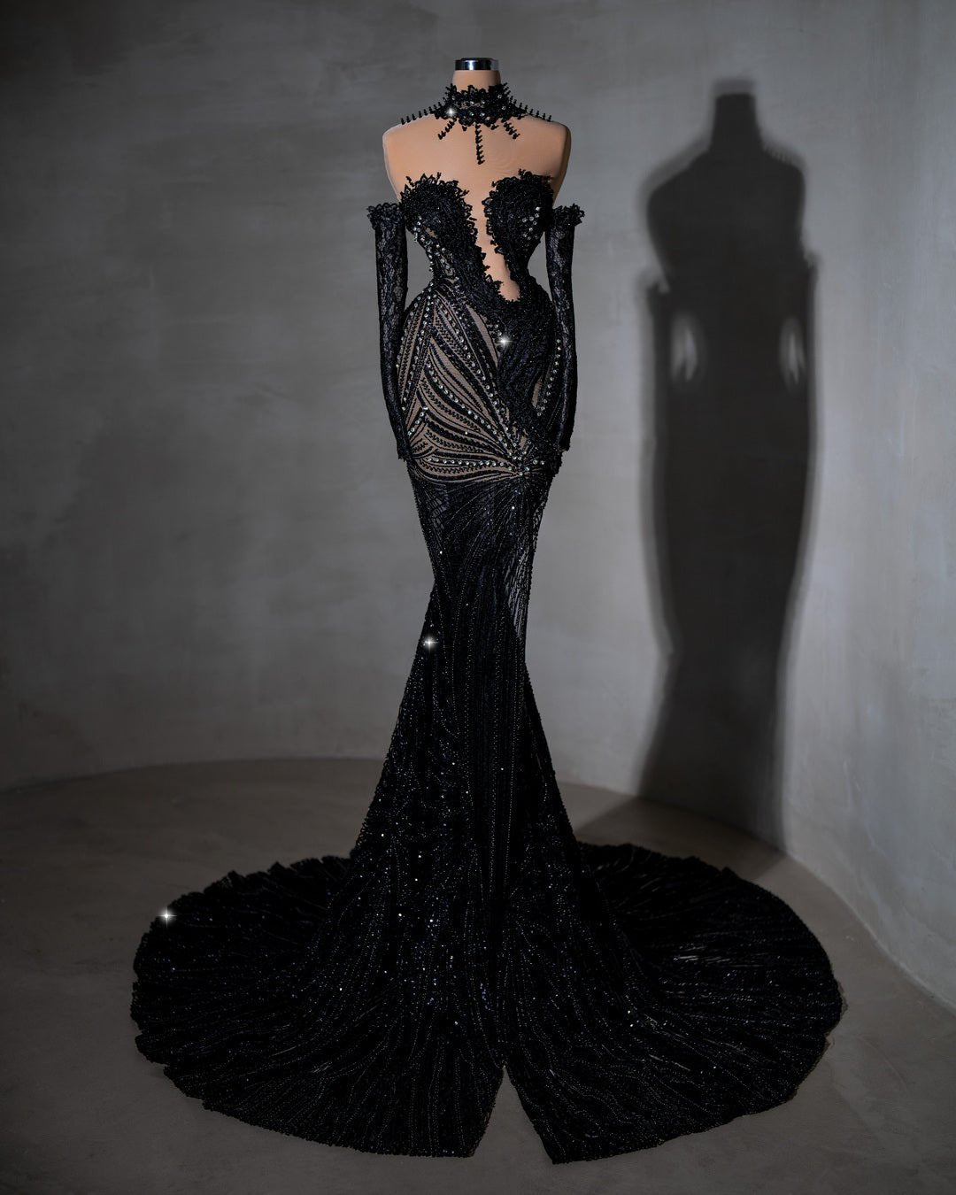 Sheer black dress with intricate beading and off-shoulder sleeves.
