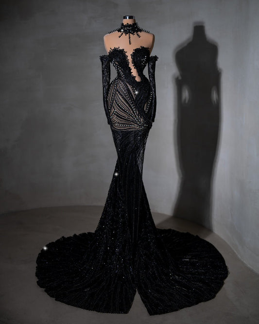 Sheer black dress with intricate beading and off-shoulder sleeves.