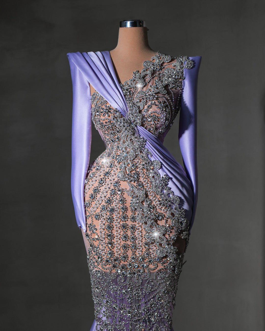A lavender gown adorned with shimmering crystal embellishments and an asymmetrical draped design.