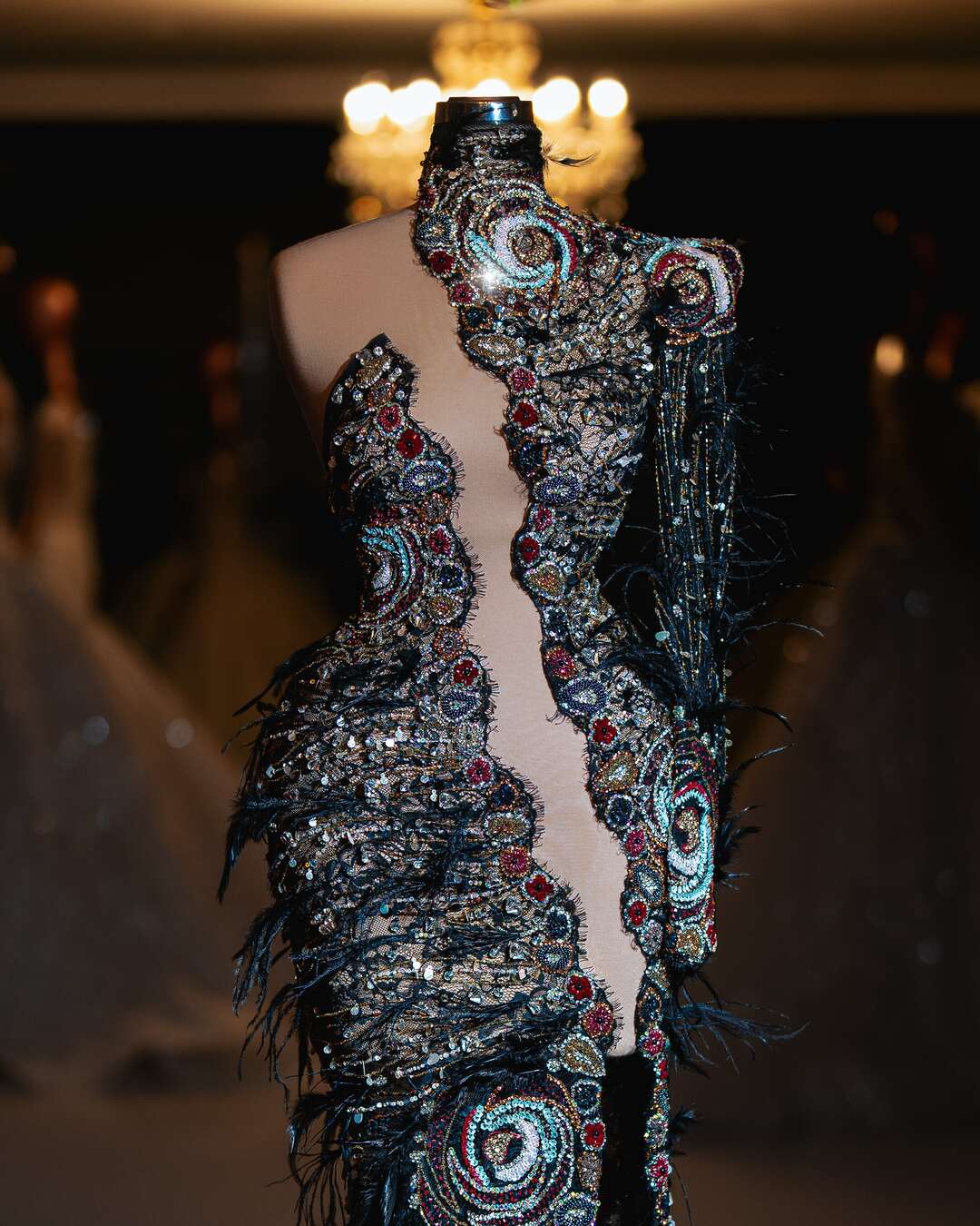 Intricate couture gown with bold beadwork and black feathers.