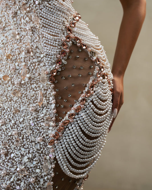 Detailed view of cutouts and pearl accents on elegant white dress