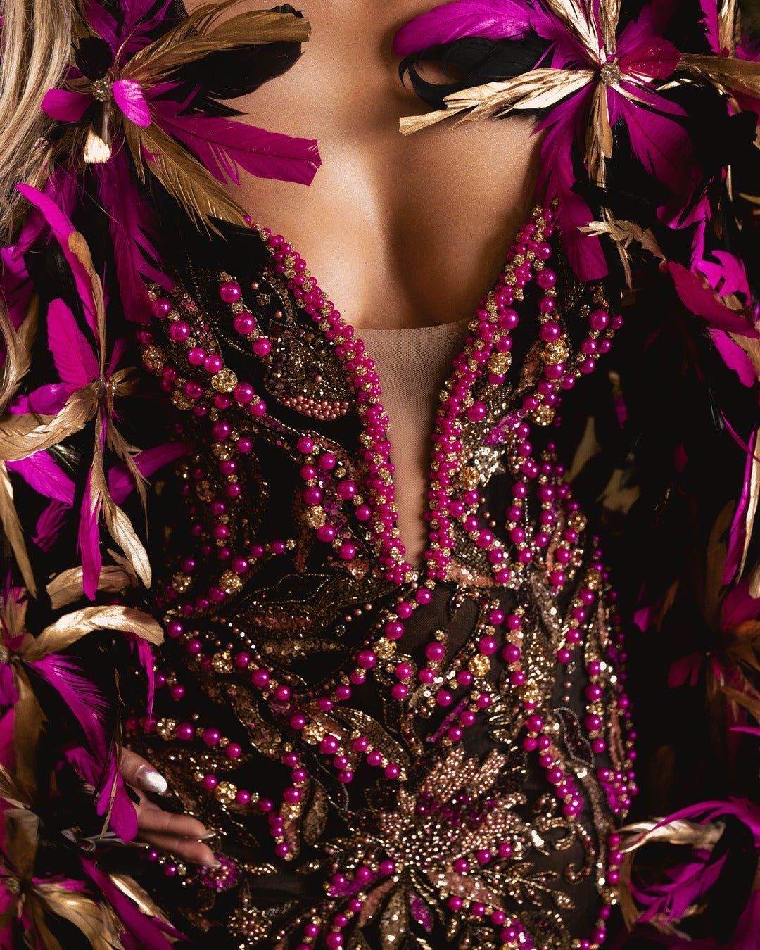 Close-up detail of black dress fabric with gold sequins and pink bead accents