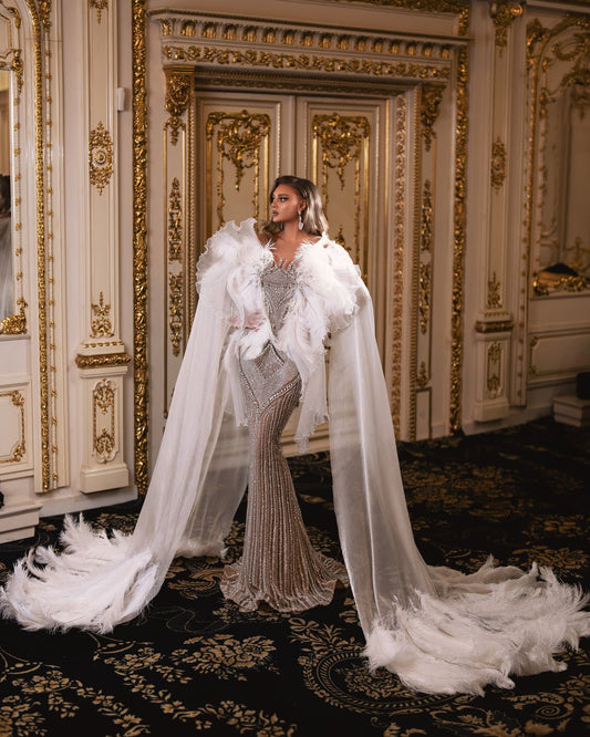 Off-the-shoulder white gown with flowing organdy capes and feather embellishments