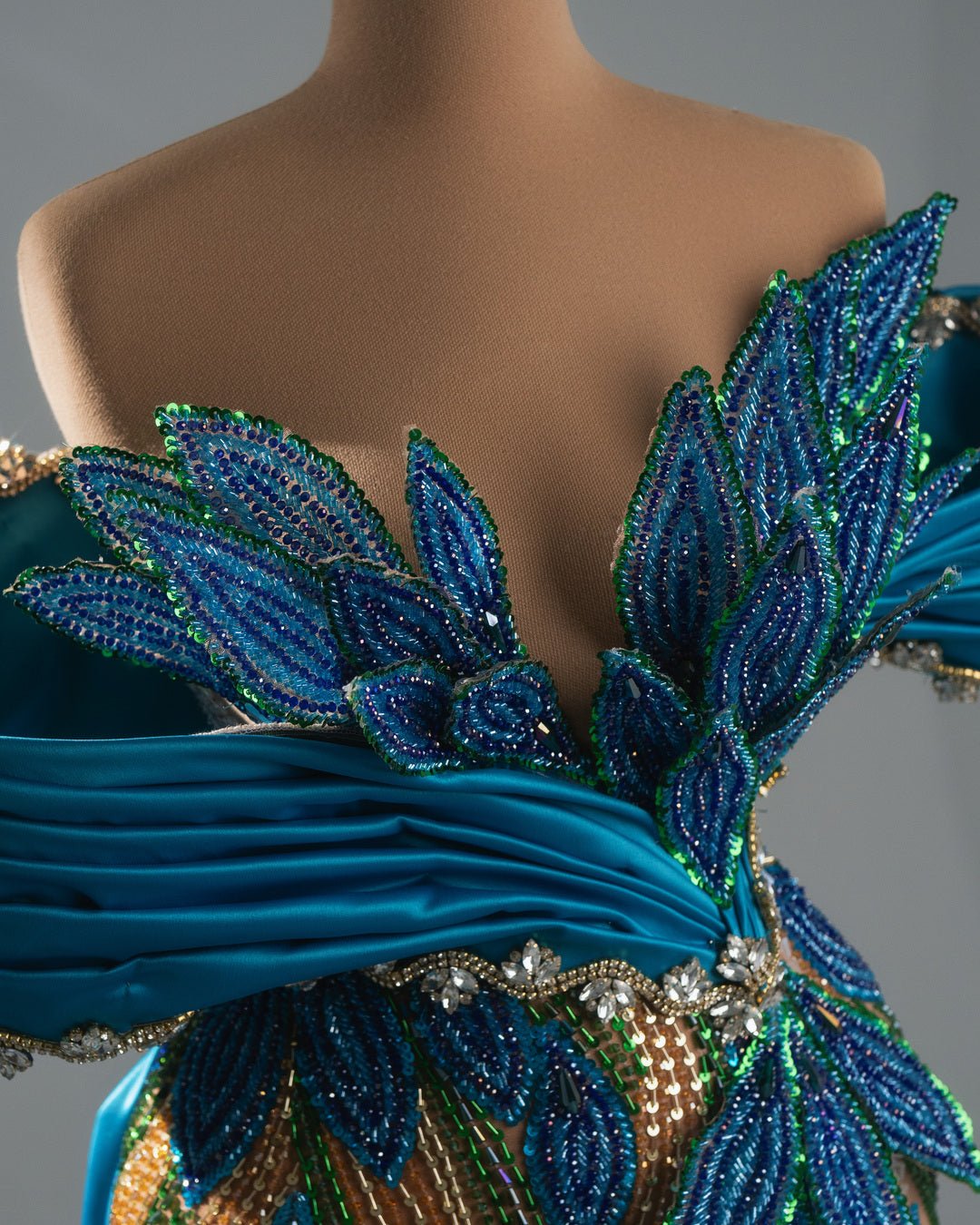 Elegant draped blue gown featuring intricate crystal leaf motifs