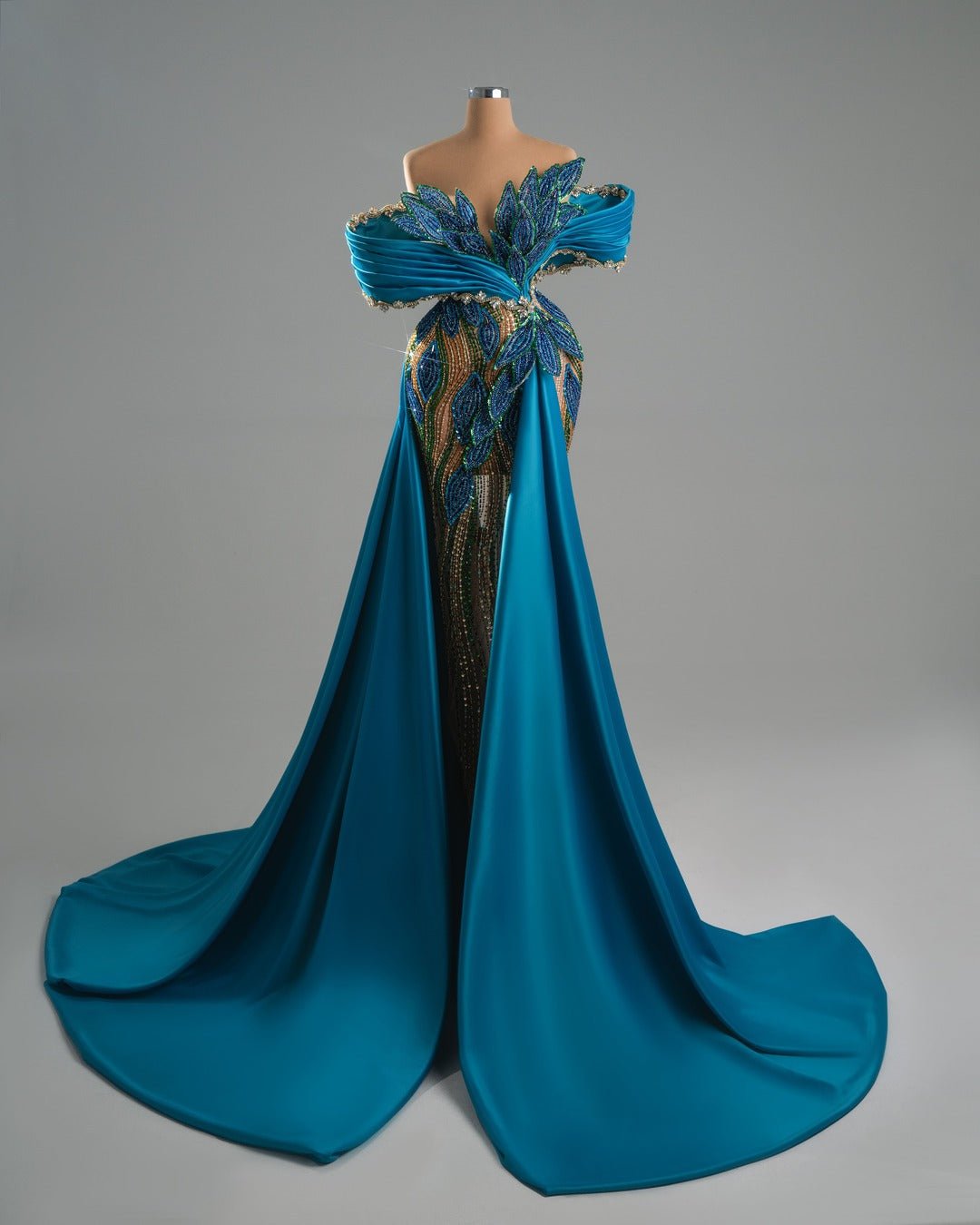Handmade blue off-shoulder dress with crystal leaf detailing and flowing train.