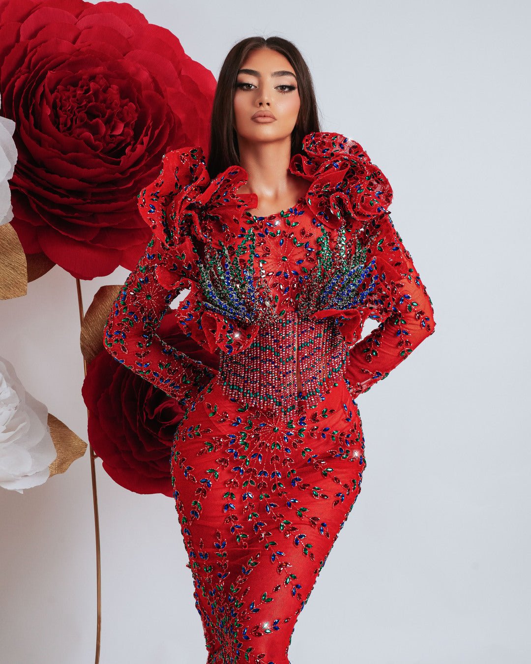 Luxury red dress embellished with stones and beads, featuring dramatic 3D ruffle shoulder design