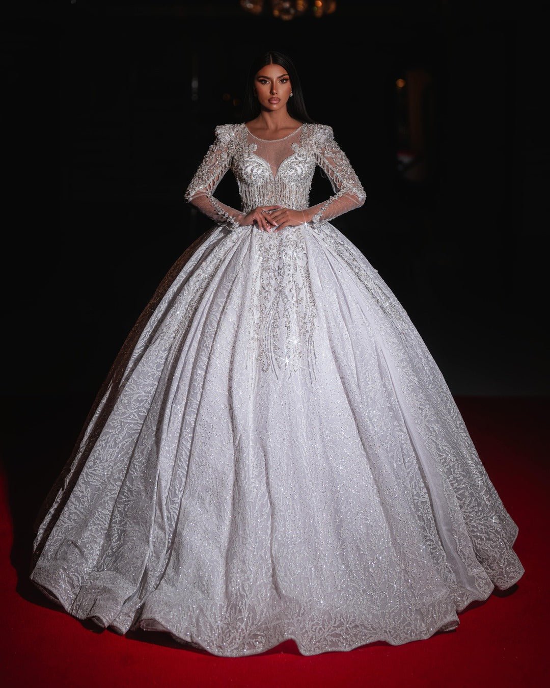 
Bride wearing an elegant white ball gown with long sheer sleeves and intricate embroidery.