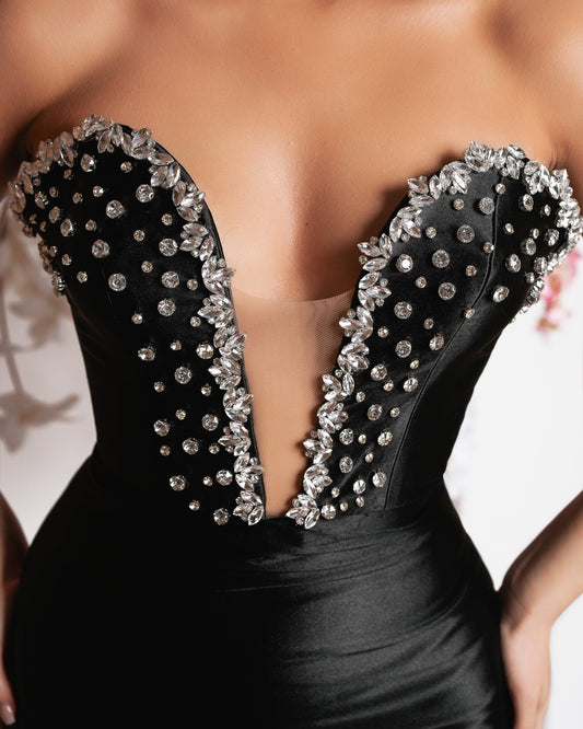 Close-up detail of luxurious black satin dress - showcasing intricate stone embellishments.
