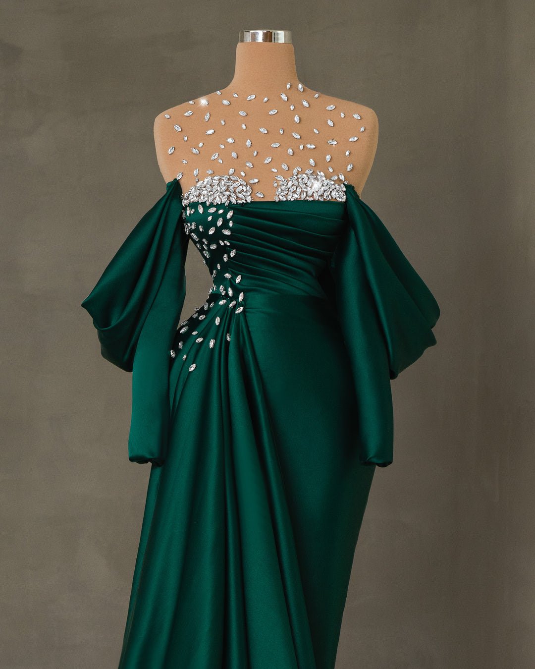 Long emerald green satin dress with off-shoulder design and crystal embellishments