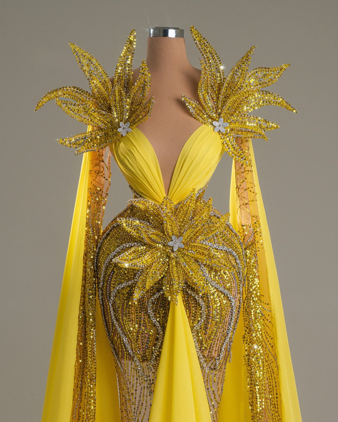 Long yellow dress with floral embroidery, open chest, and shoulder cape.