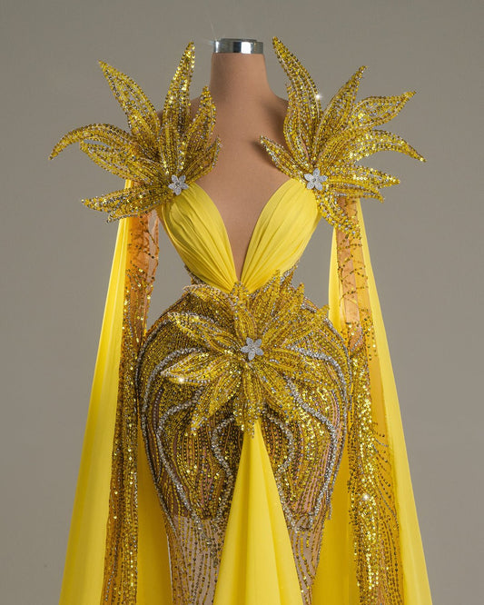 Long yellow dress with floral embroidery, open chest, and shoulder cape.