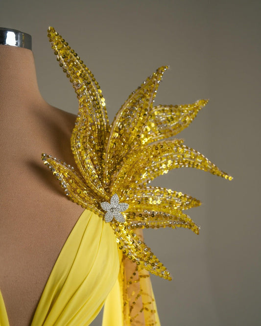 Elegant yellow dress with floral design, open chest, and cape.