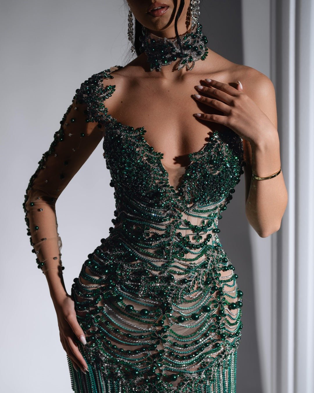 Close-up of the intricate tassel and bead detailing on the green dress.