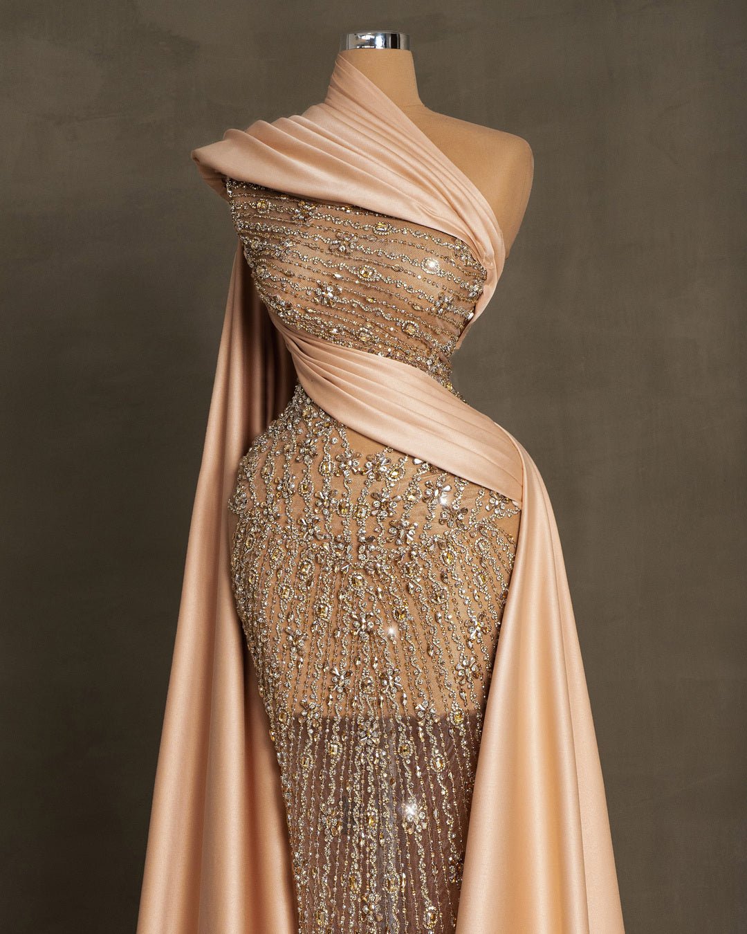 Elegant champagne dress with lace embellishments, stones, crystals, and side cape in satin fabric