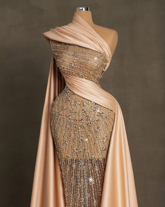 Elegant champagne dress with lace embellishments, stones, crystals, and side cape in satin fabric