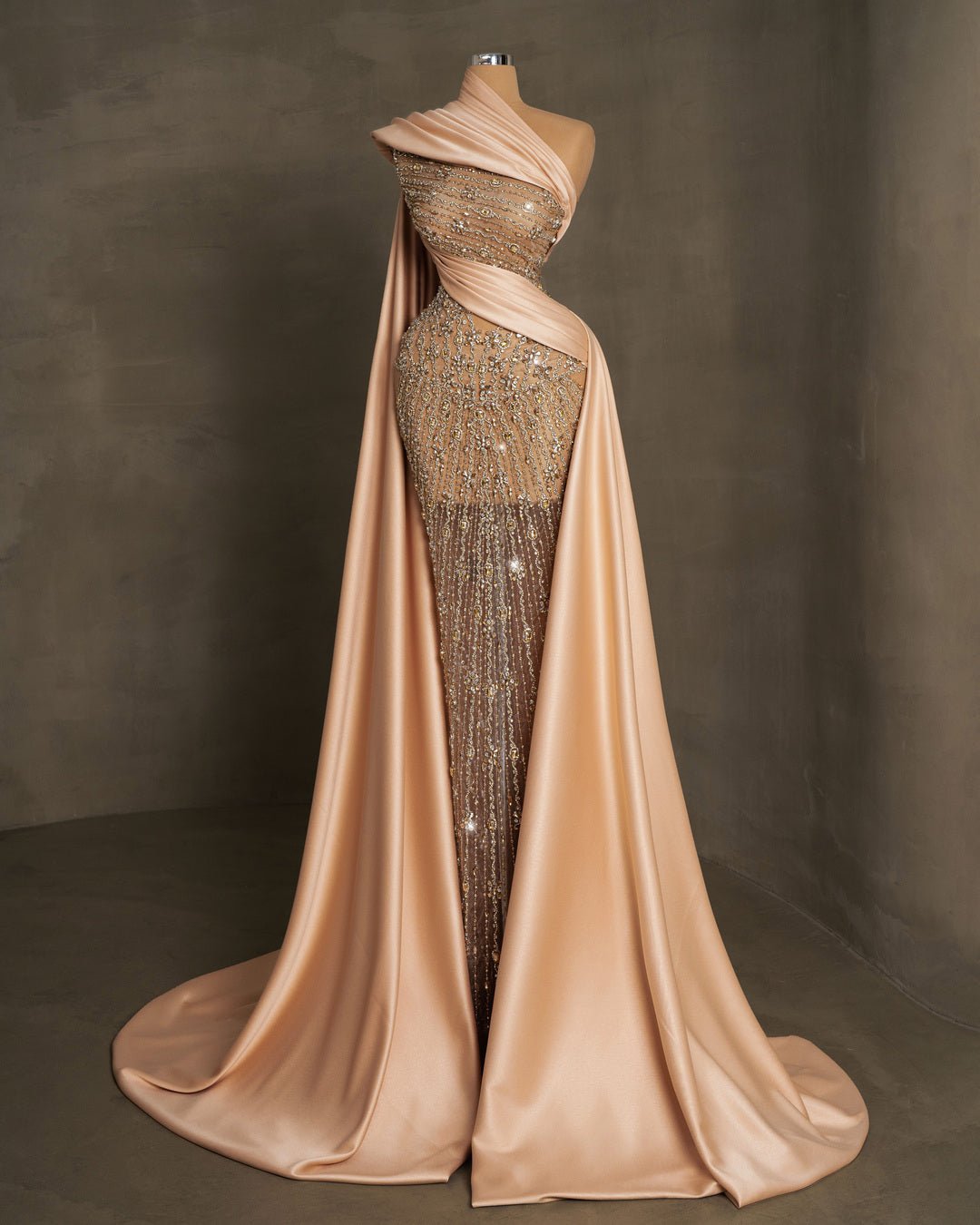 Luxurious long champagne dress adorned with stones and crystals, featuring side cape and tail in satin fabric