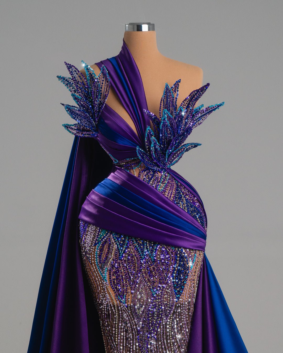 Deep purple and royal blue evening gown with intricate beadwork and a leaf-like design.