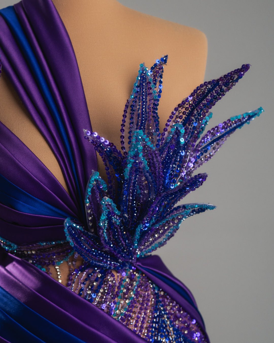 Fitted silhouette with sheer, embellished lower section and dramatic asymmetrical neckline.