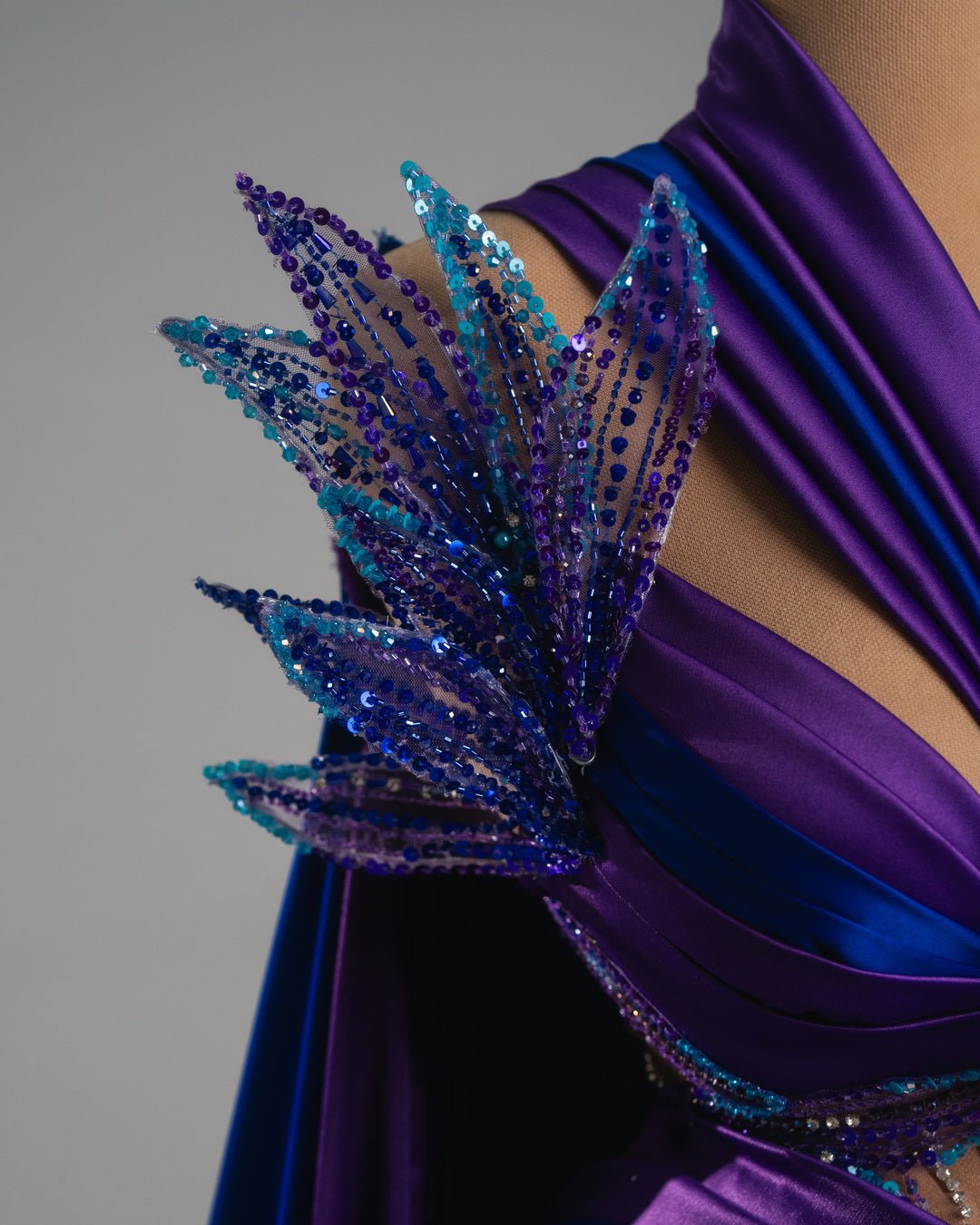 Vibrant violet and blue dress with sparkling embellishments and regal feather-inspired details.