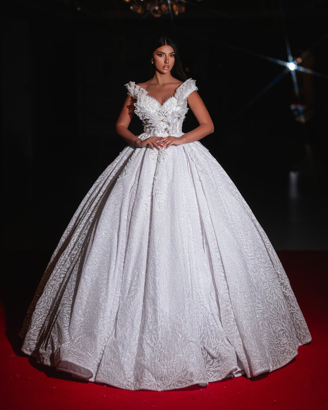 A shimmering off-shoulder bridal ball gown with floral appliqués and a voluminous skirt.
