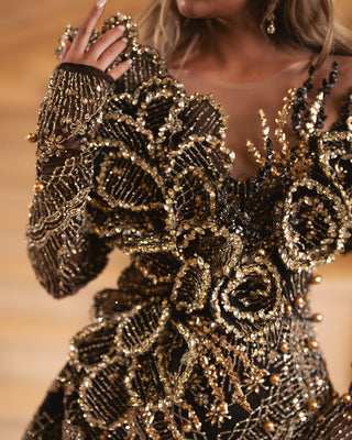 Close-up detail of intricate gold beadwork on black lace dress