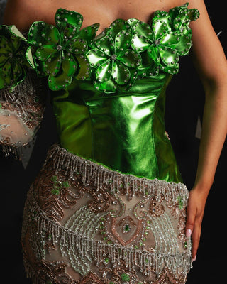 Close-up of intricate crystal and stone detailing on green dress bodice