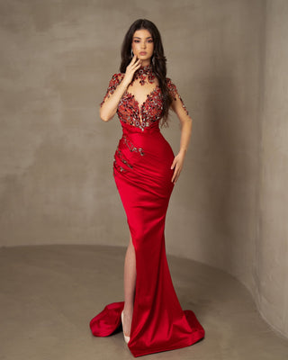 xquisite red dress with a lace-embellished bodice, crystals, and a satin skirt, boasting long sleeves and a dramatic deep slit.