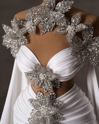 Close-up of bridal dress details: crystals, pearls, side cape, and cut-outs.