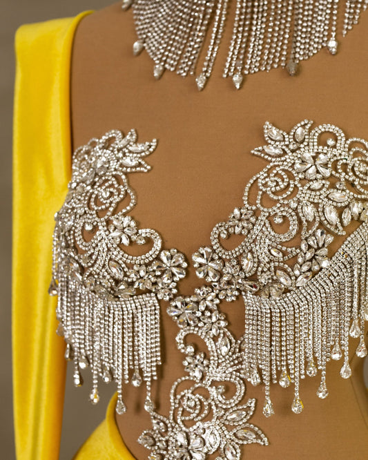 Close-up of silver-embellished bodice with crystals and tassels on yellow velvet dress.