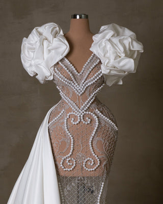 Elegant lace bridal gown adorned with pearls and satin accents.