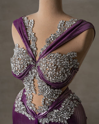 Close-up of shimmering purple fabric and intricate silver crystal detailing on elegant gown
