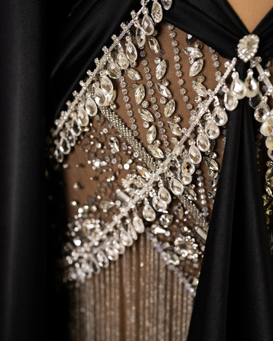 Detailed shot of the Black Dress, highlighting the exquisite long sleeves and shimmering gemstone embellishments