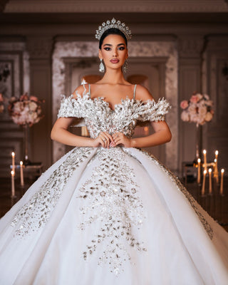 Elegant bridal gown featuring off-shoulder design and luxurious lace embellished with crystals.